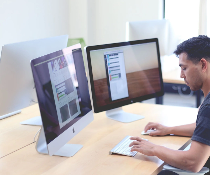 Man crafting content with Surfer SEO at a desk equipped with dual monitors.