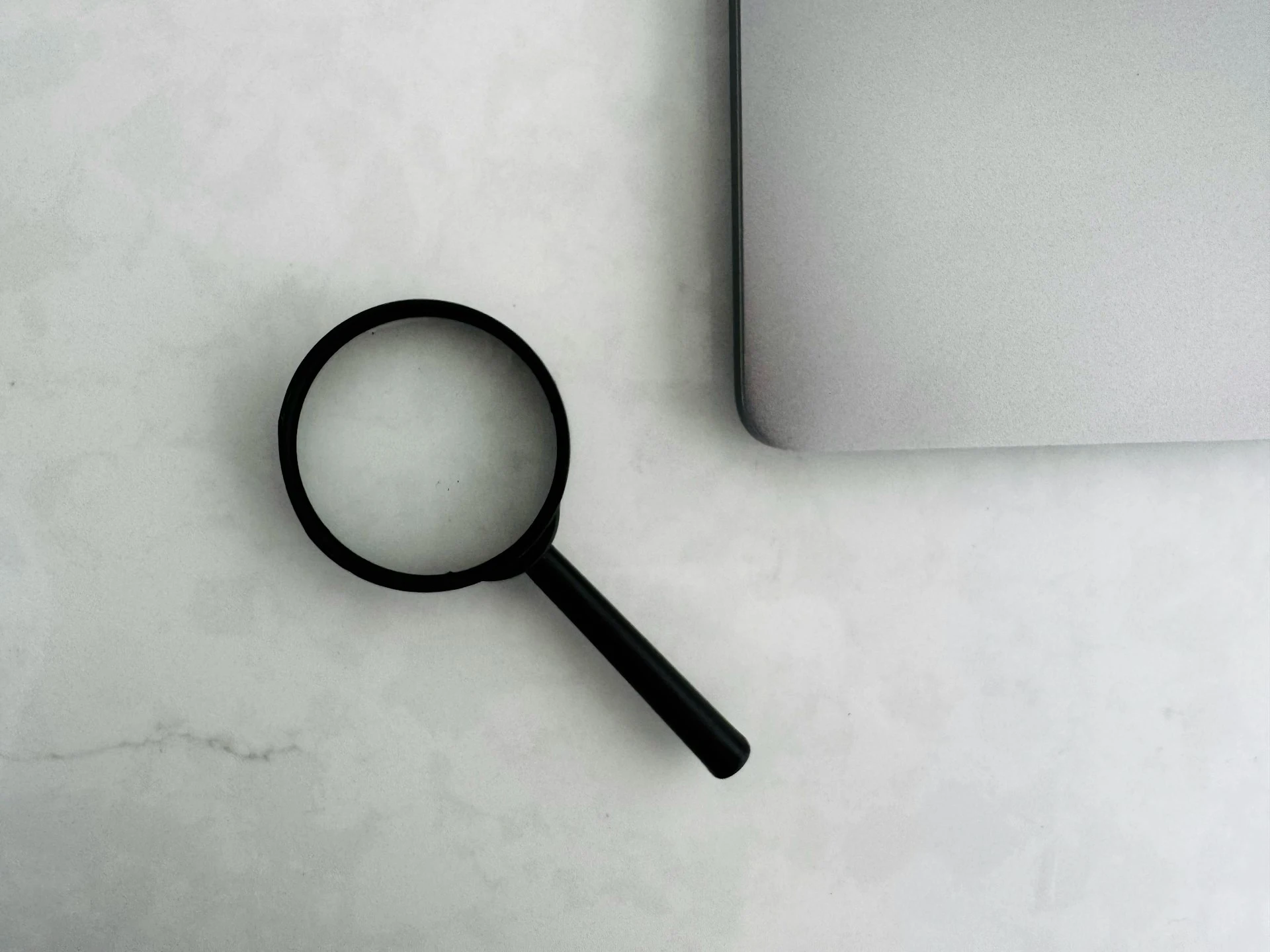 Magnifying glass sits near a laptop on a table
