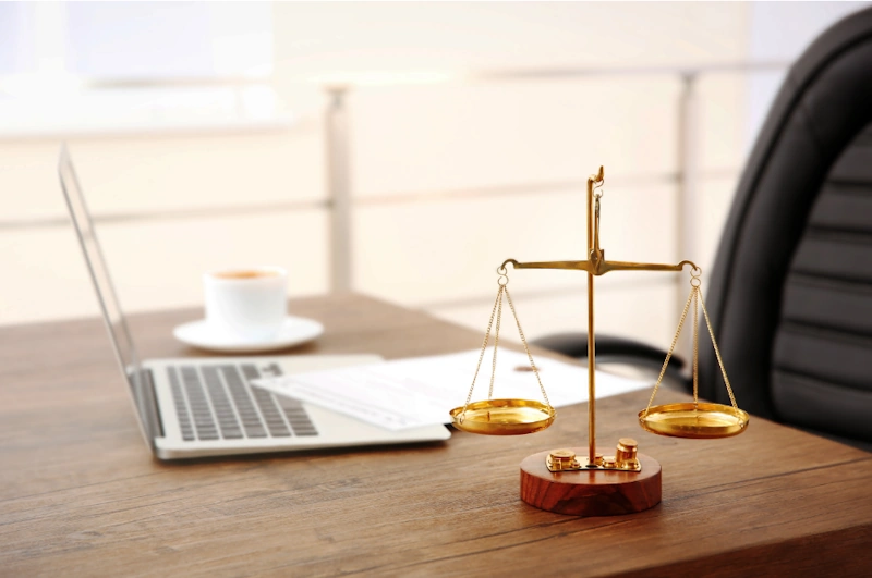 A laptop open on a lawyer's desk next to a golden scales of justice symbol, representing digital SEO for lawyers.